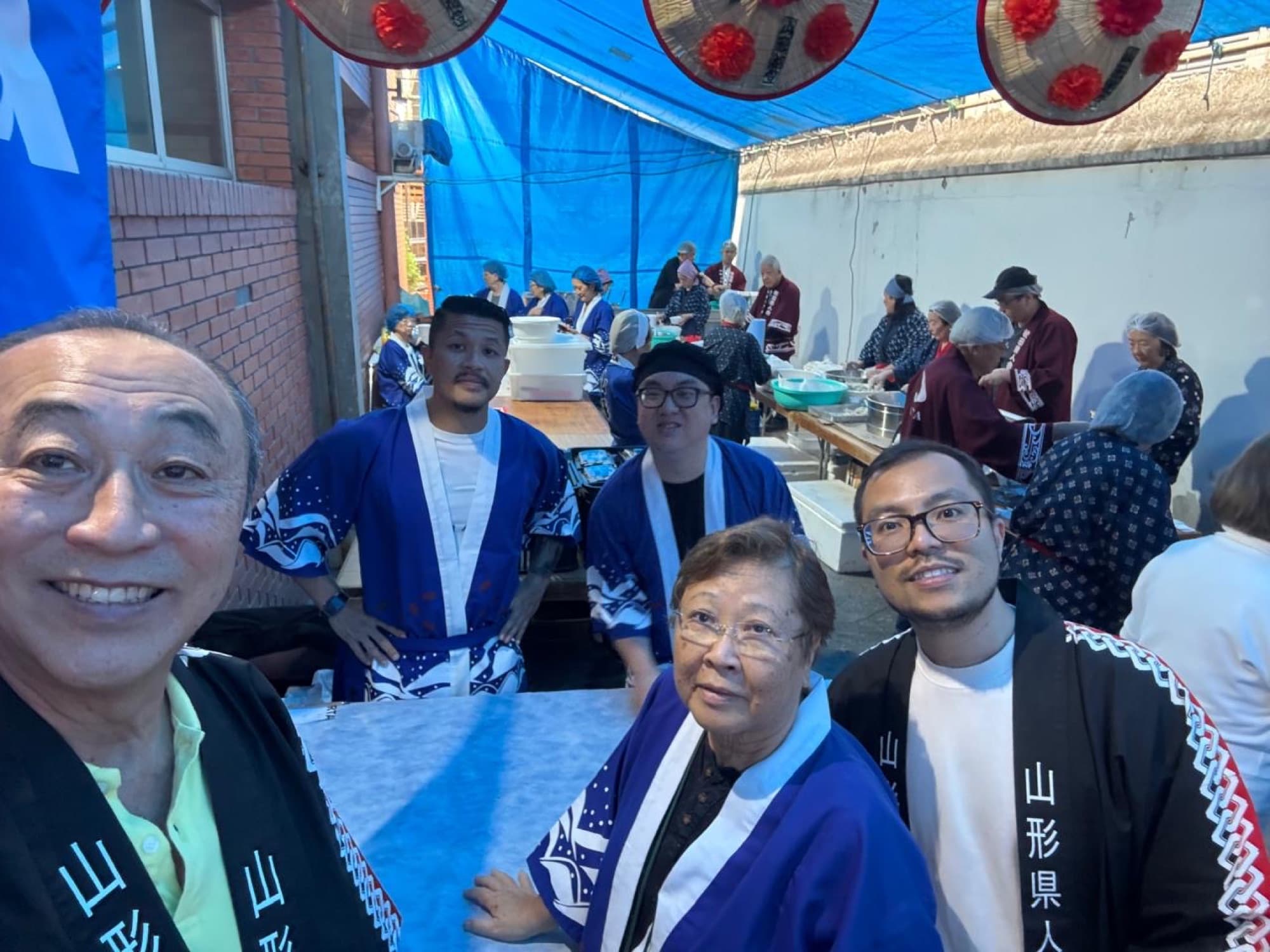 Grupo de associados da Yamagata Kenjinkai com a faixa 山形県人 durante o festival